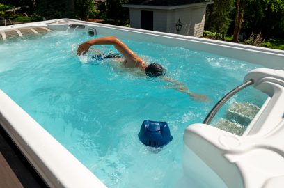 Swimmer in swim spa next to FROG @ease for Swim Spas Sanitizing System